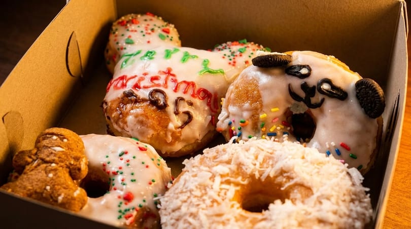 A box of festive donuts, including one with "Merry Christmas 25" icing and a panda-decorated donut.